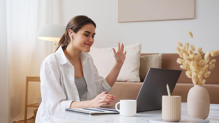 Femme souriante saluant lors d'un appel vidéo en visio, pour une séance d'accompagnement en ligne.